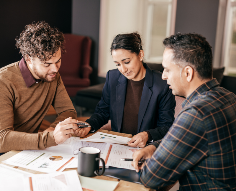 two men signing up for mortgage with loan officer
