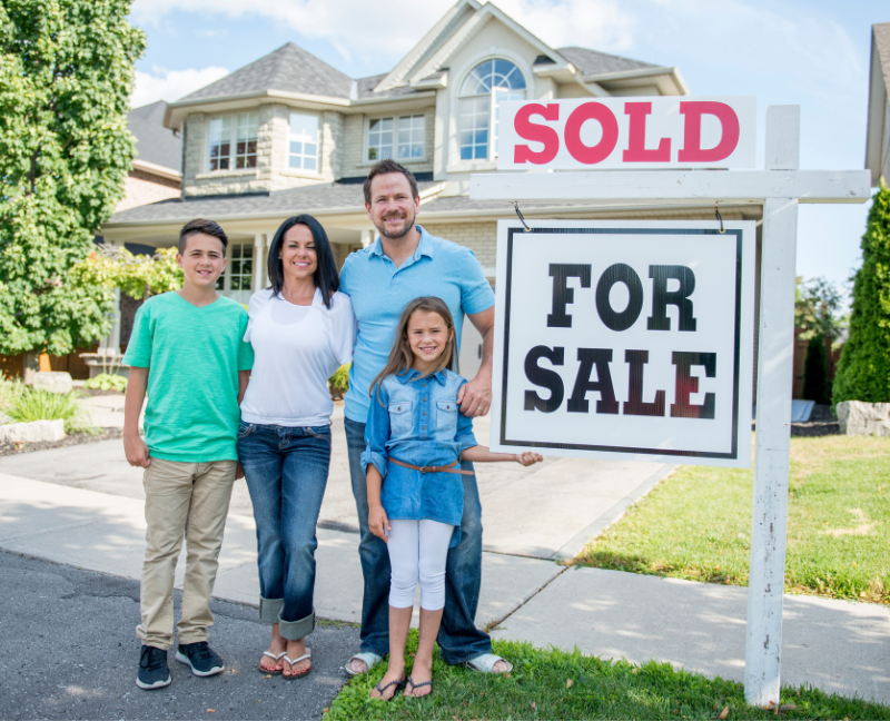 family in front of sold for sale home sign
