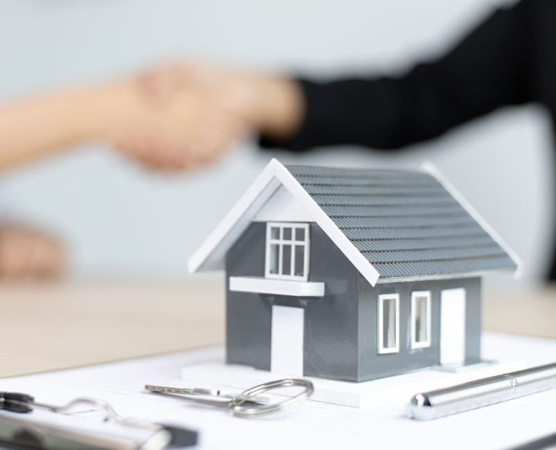 shaking hands with agent and showing a miniature house