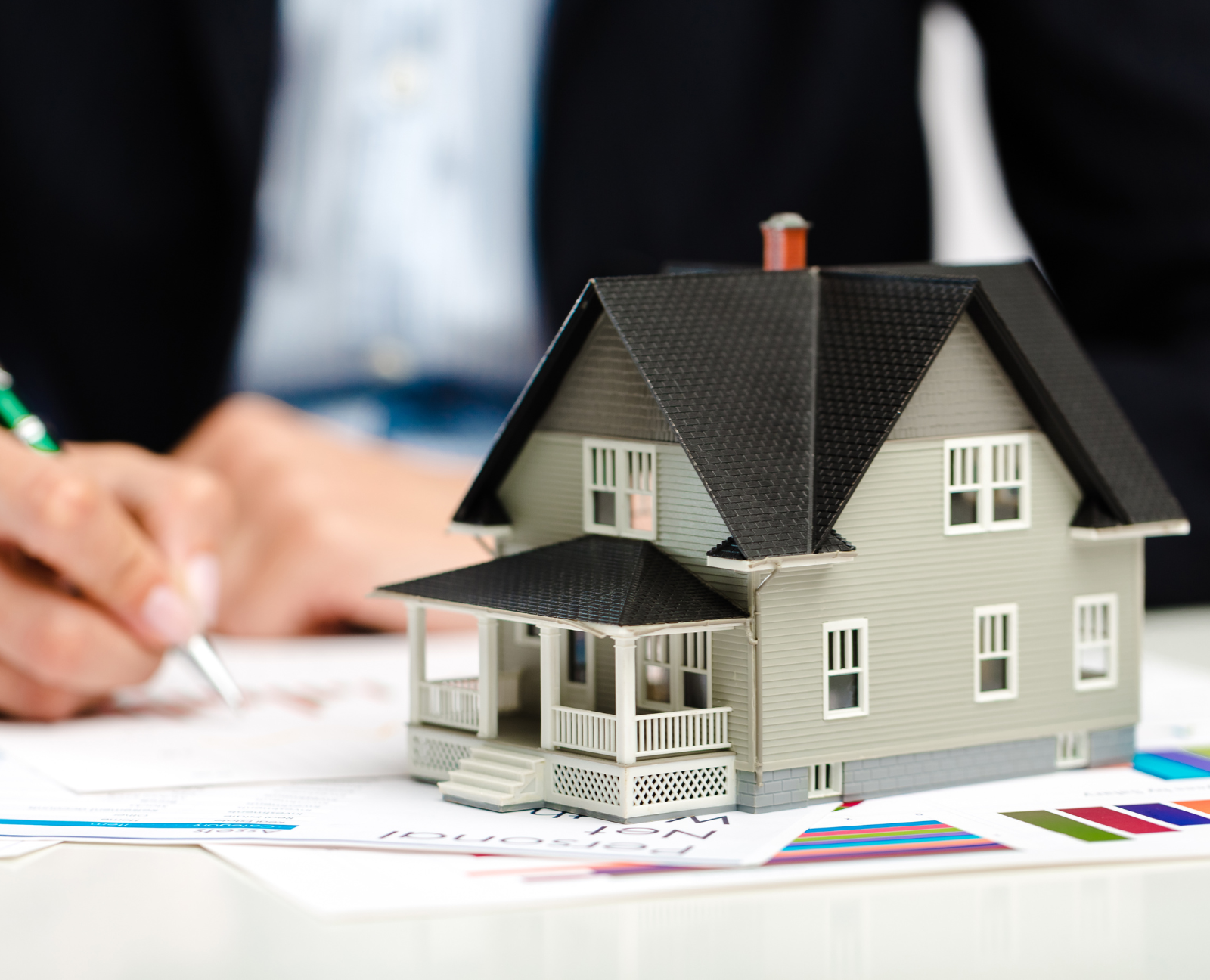 real estate agent signing papers with small house model
