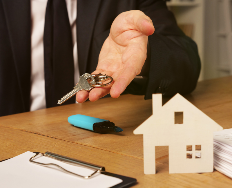 real estate agent holding house heys with miniature house